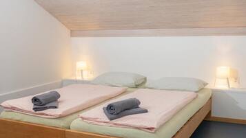 Ein Einzelbett mit zwei Kissen, einem hölzernen Kopfteil und zwei Nachttischlampen.
