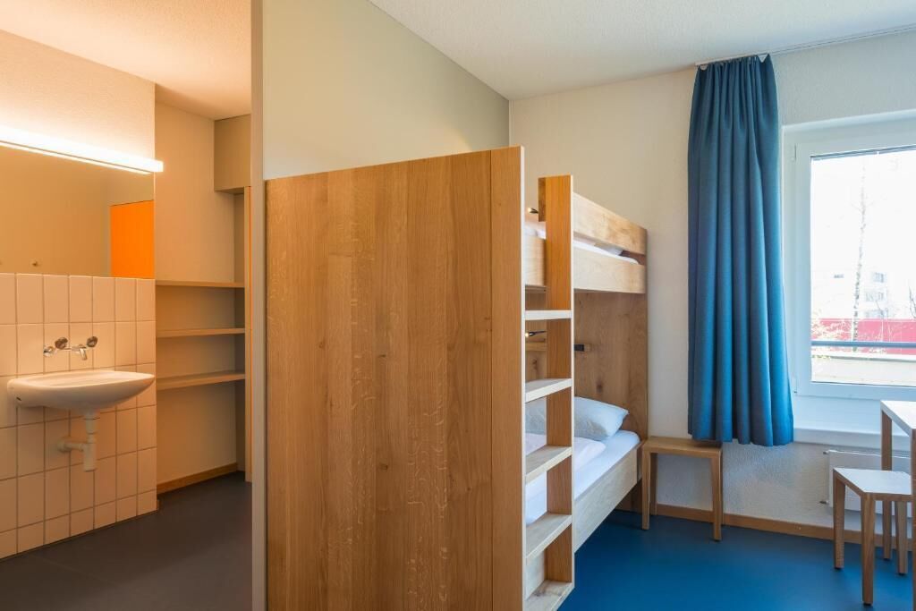 Ein Zimmer mit einem Etagenbett, einem Waschbecken und einem Fenster mit Vorhängen.