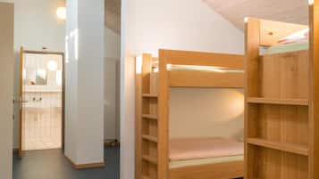 Una habitación con literas y una estantería de madera.