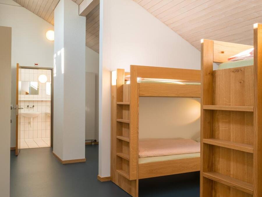 Una habitación con literas y una estantería de madera.