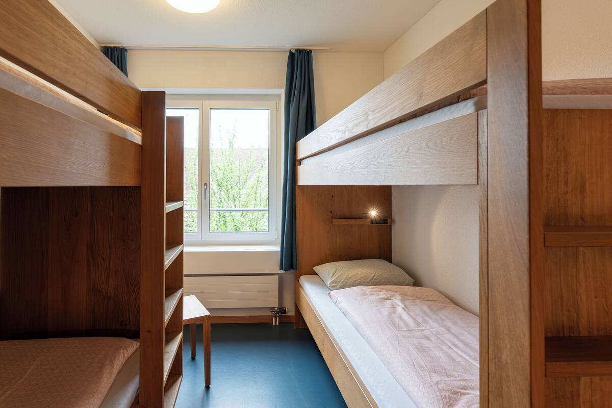 Habitación con literas, una ventana, un escritorio y un radiador.
