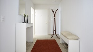 Ein Flur mit einer weißen Bank, einem Kleiderständer und einem Spiegel an der Wand.