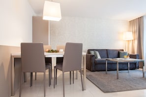 Uma sala de estar moderna com área de jantar, apresentando um sofá, uma mesa de centro e uma mesa de jantar com cadeiras.
