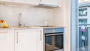 Una cucina moderna con mobili bianchi, un forno in acciaio inossidabile e un'ampia finestra che offre vista all'esterno.
