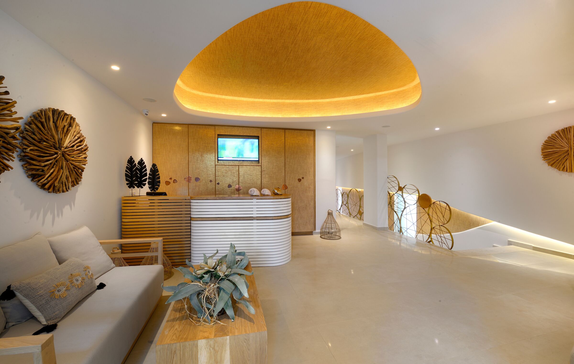 A modern hotel lobby with a reception desk, a sofa, and decorative wall art.