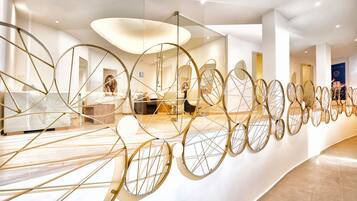 Un intérieur moderne agrémenté d’une longue rangée de décorations murales rondes, d’un espace d’accueil avec un comptoir et d’un coin salon avec des chaises.