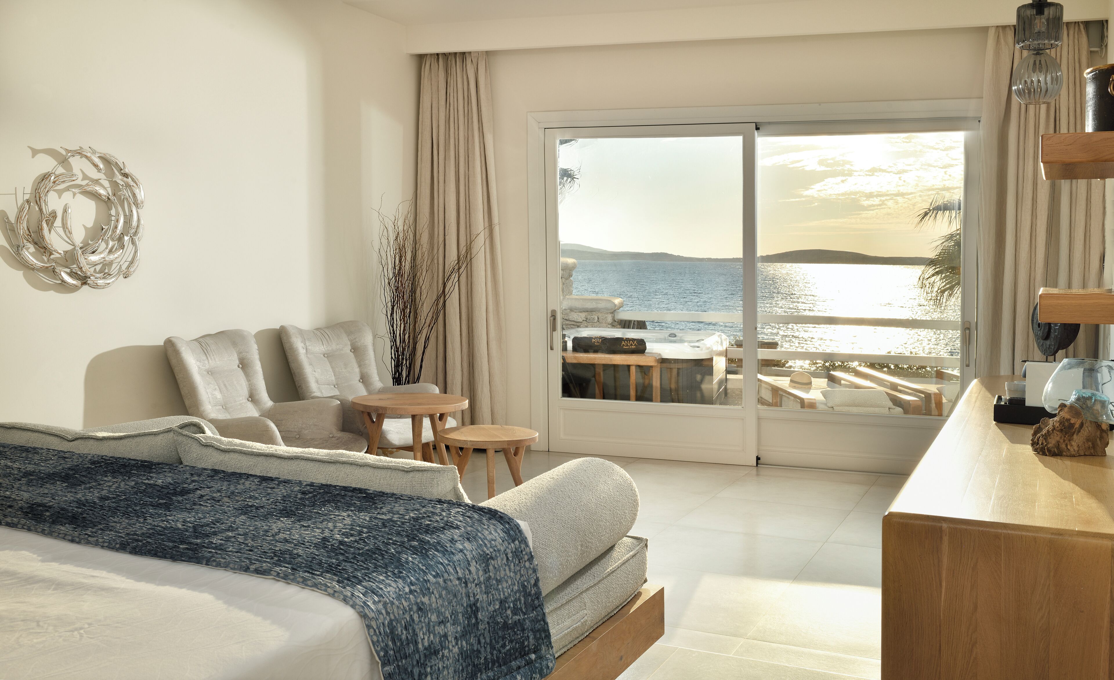 A bedroom with a large bed, a small table, and a view of the sea.