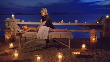 Sesión de masajes en la playa, con velas y vistas al mar.