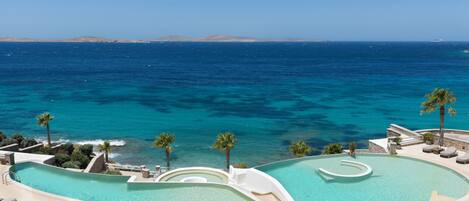 A resort with a large infinity pool, palm trees, and a view of the ocean.