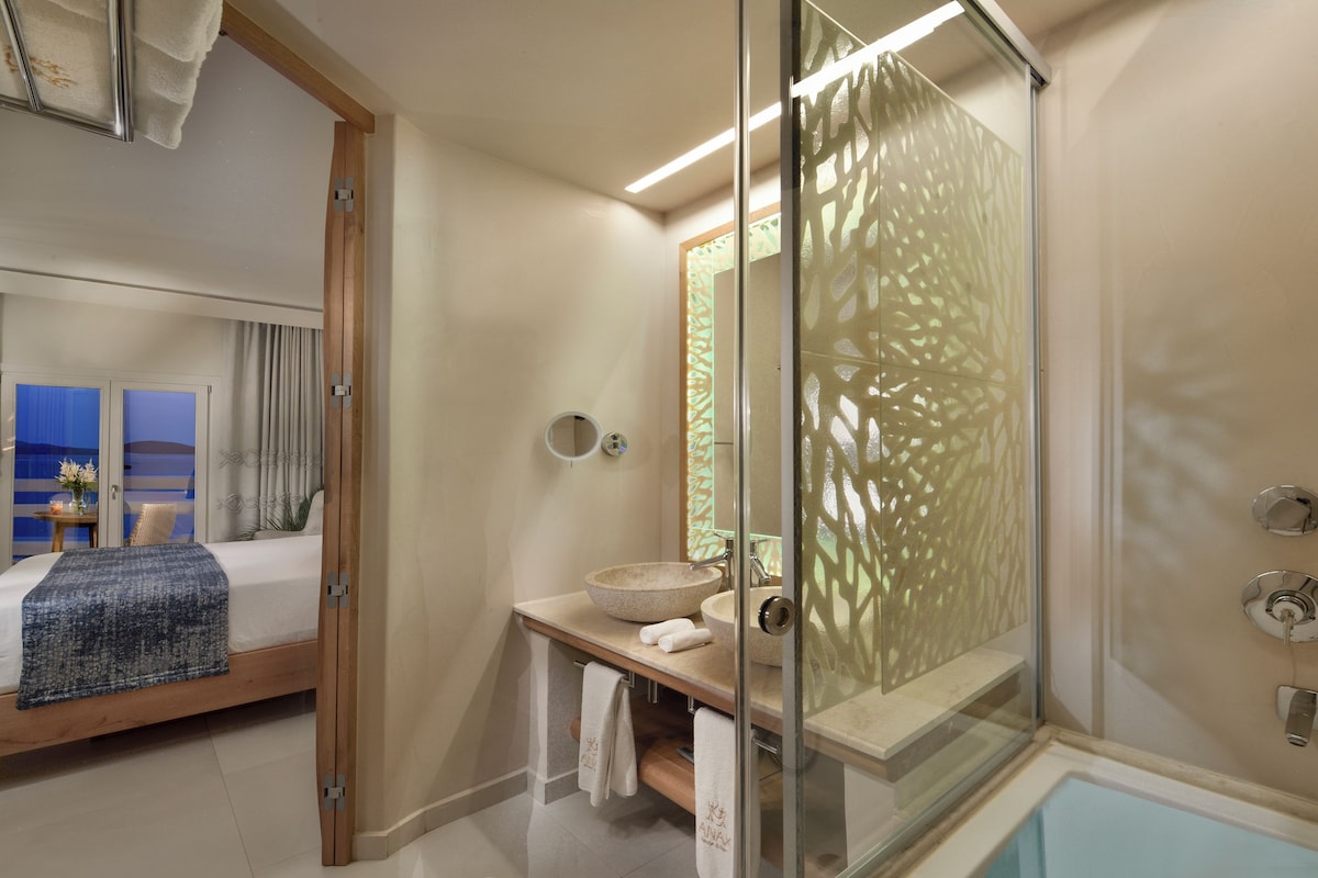 A modern bathroom with a glass-enclosed shower, a large round sink, and a bathtub.