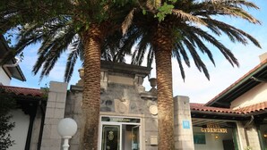 The entrance to a hotel with a stone facade, palm trees, and a sign that reads "GUDAMENDI." - Hotel Gudamendi (San Sebastián)