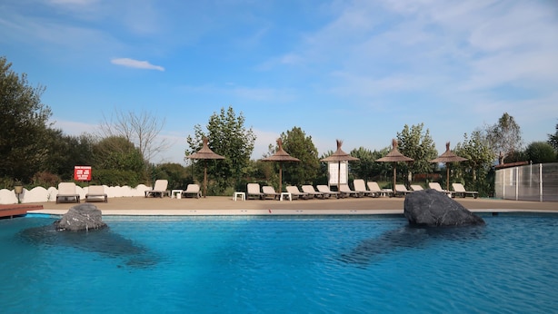 A swimming pool with lounge chairs and umbrellas, surrounded by trees and a clear sky. - Hotel Gudamendi (San Sebastián)