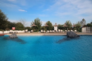 A swimming pool with lounge chairs and umbrellas, surrounded by trees and a clear sky. - Hotel Gudamendi (San Sebastián)