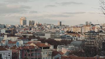 A cityscape with a mix of residential and commercial buildings, including high-rise structures and smaller houses with red-tiled roofs.
