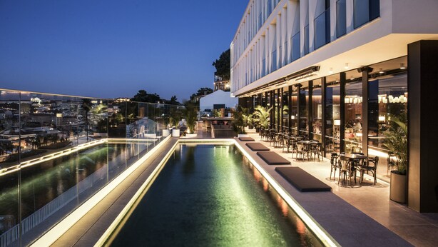 A rooftop pool area with a bar and seating, overlooking a cityscape. - Memmo Príncipe Real - Design Hotels (Lisbon)