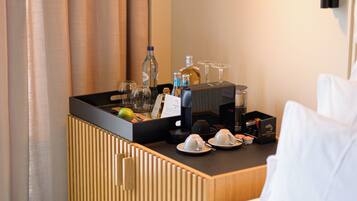 A hotel room with a minibar, a coffee machine, and a bottle of water.