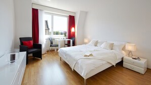 A modern hotel room with a large bed, bedside tables, a desk, and a chair. - City Stay Apartments Forchstraße (Zürich)