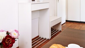 A hotel room with a white vanity, a mirror, a door, and a breakfast setup with a croissant and a cup. - City Stay Apartments Forchstraße (Zürich)