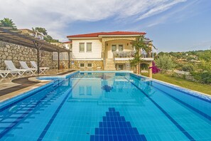 Una piscina al aire libre, sombrillas, sillones reclinables de piscina