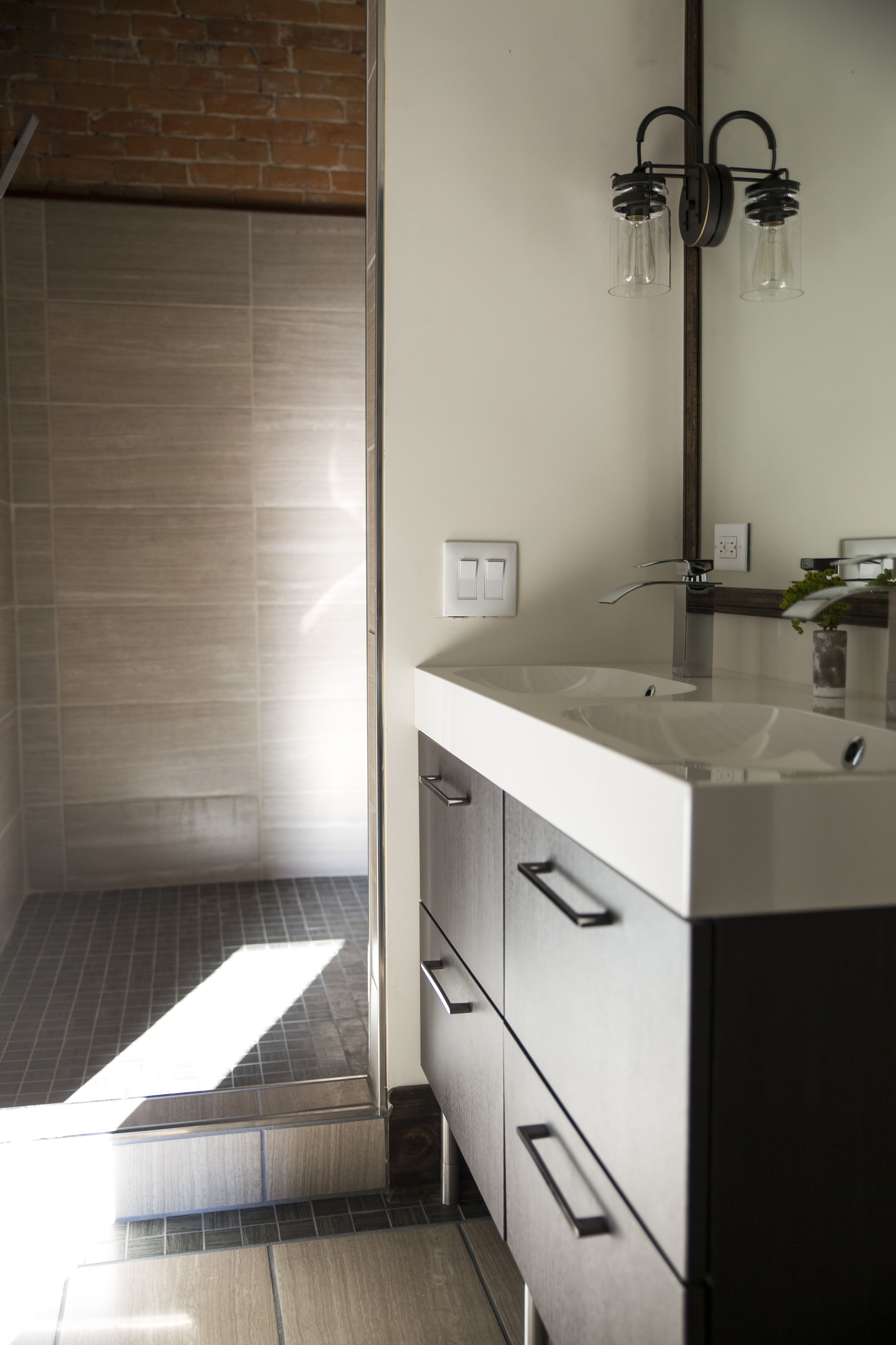 A modern bathroom with a large mirror, a white sink, and a shower area.