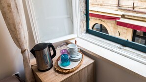 A kitchen counter with a kettle, cups, and a blue glass jar on a woven mat. - Rooms Tezoro (Dubrovnik)