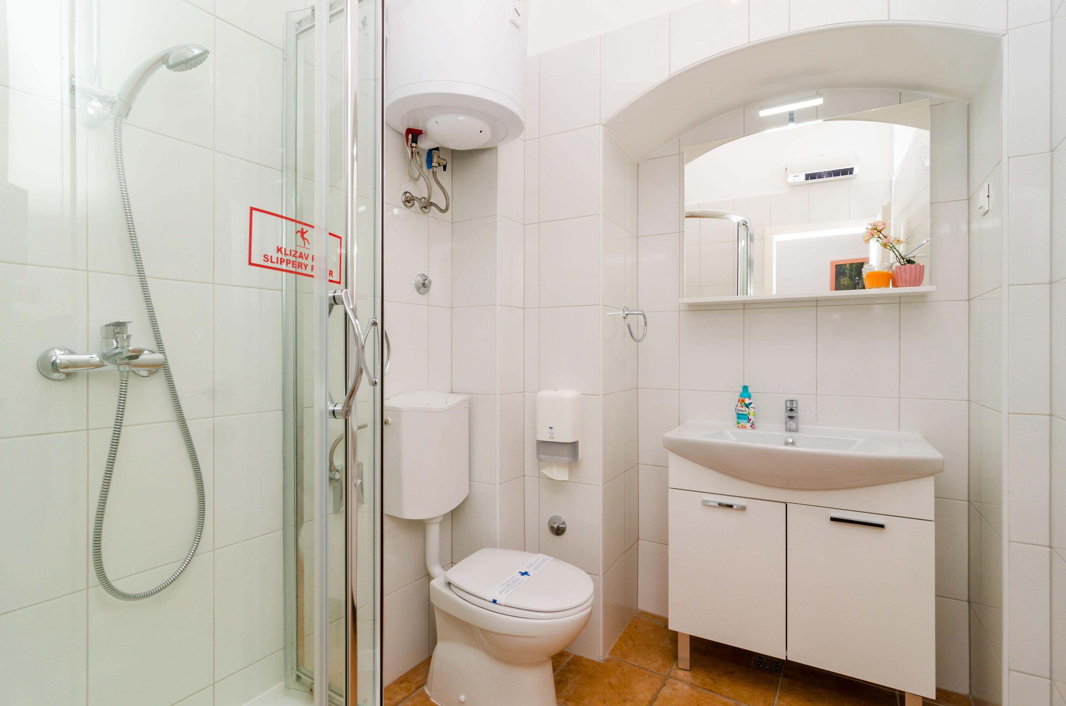 Een moderne badkamer met een douchecabine van glas, een toilet, een wastafel en een spiegel.