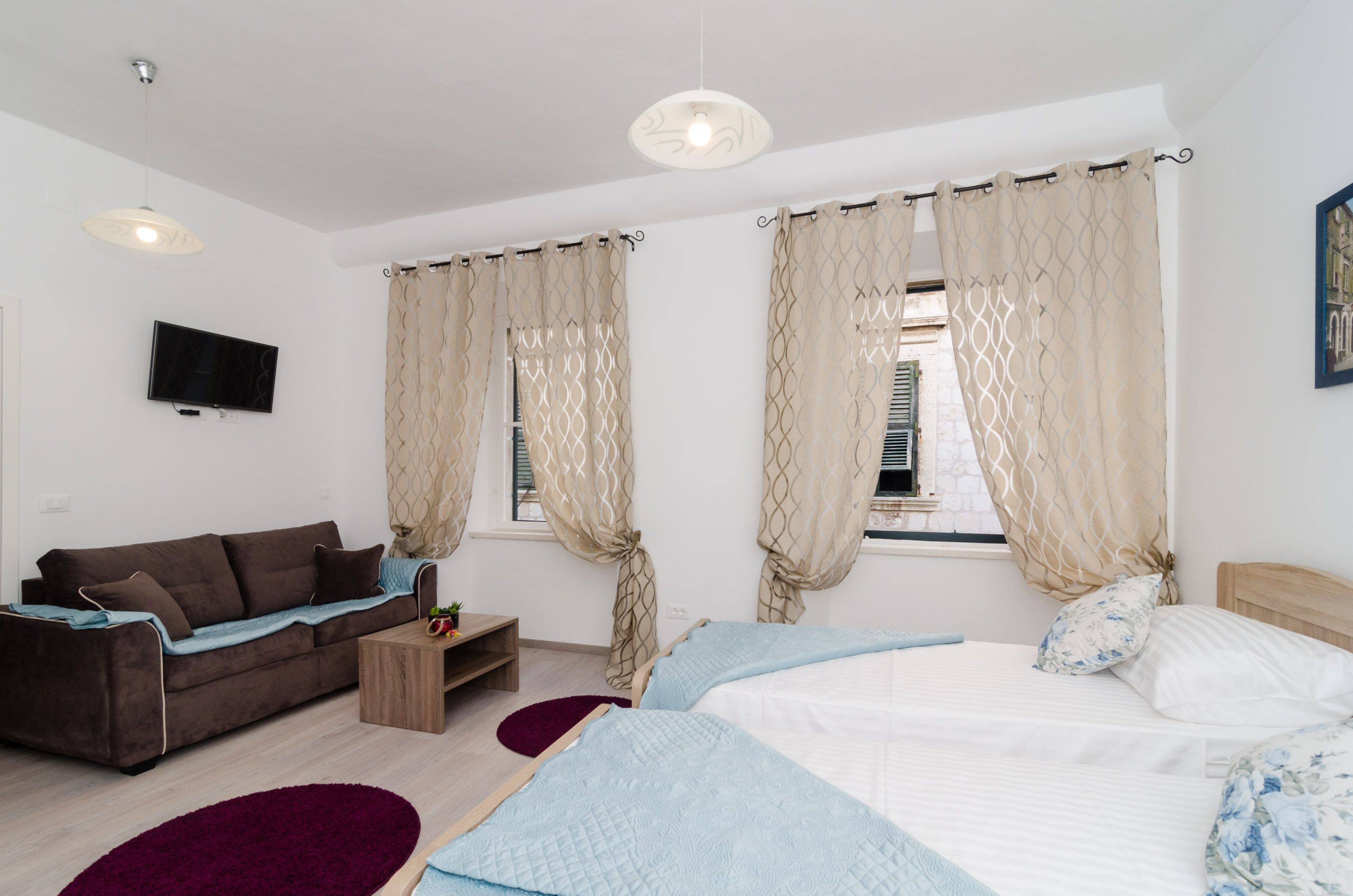Une chambre d’hôtel moderne équipée d’un lit, d’un canapé, d’une télévision et d’une fenêtre avec des rideaux.