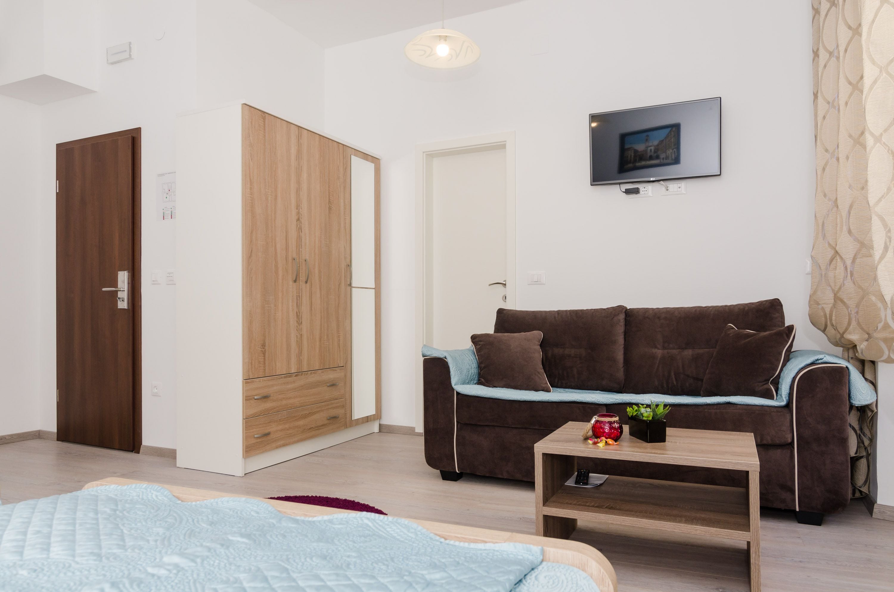 A modern living room with a brown sofa, a wooden coffee table, and a TV mounted on the wall.