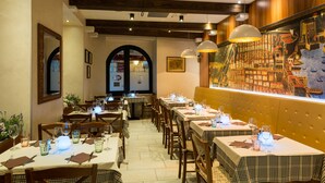 A restaurant with multiple tables set for dining, wooden beams on the ceiling, and a mural on the wall. - Rooms Tezoro (Dubrovnik)