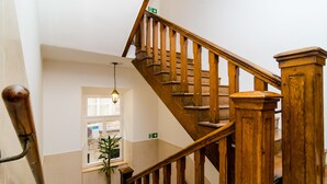 A wooden staircase with a handrail, a potted plant, and a window with a view of the outside. - Rooms Tezoro (Dubrovnik)