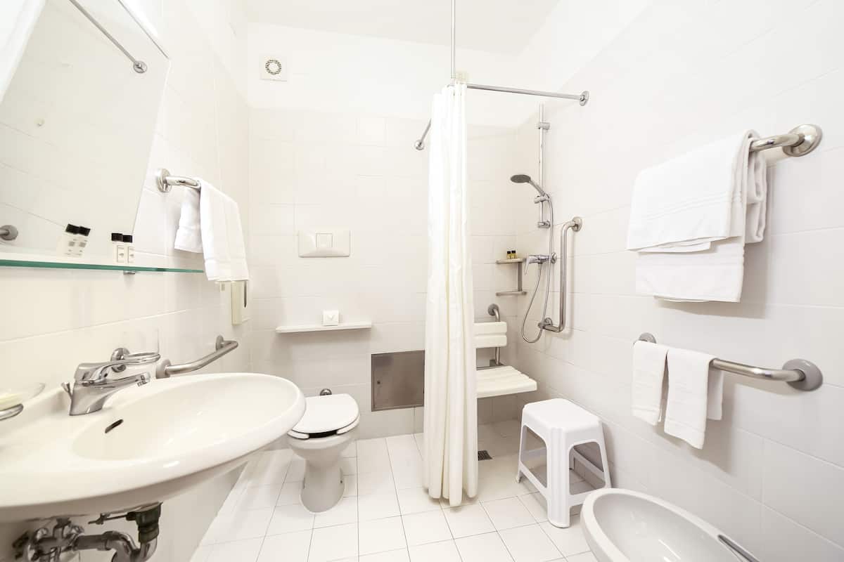 Ein modernes Badezimmer mit einer Duschkabine, einem weißen Waschbecken, einer Toilette und einer Badewanne.
