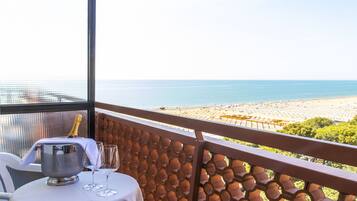 Ein Balkon mit Tisch für zwei Personen mit Blick auf einen Strand.