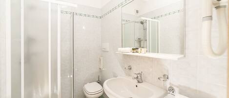 A bathroom with a glass-enclosed shower, a white toilet, and a sink with a mirror above it.