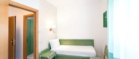 Une petite pièce propre, avec un lit, une chaise et une table de chevet.