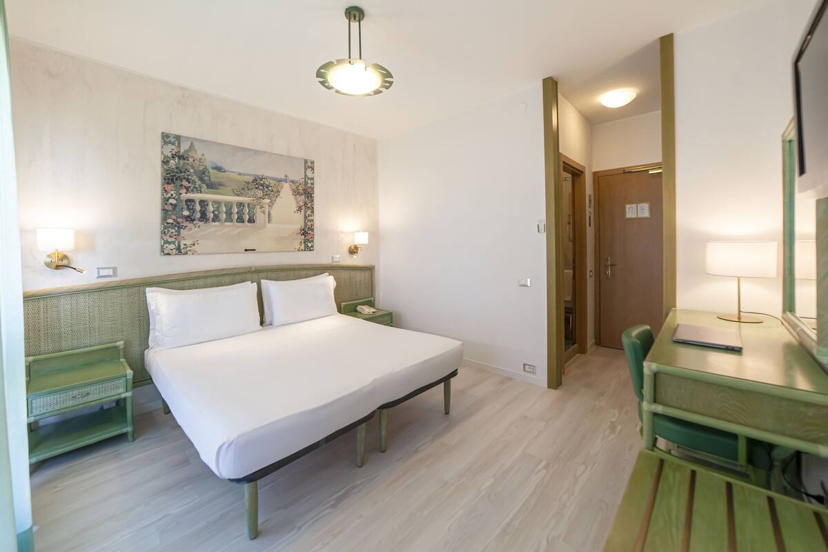 Ein Hotelzimmer mit Bett, Nachttischen, Schreibtisch und Stuhl.