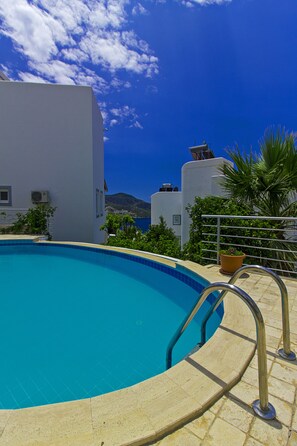 Una piscina al aire libre, sombrillas, sillones reclinables de piscina