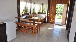 A small kitchen with a refrigerator, wooden table, and bench seating. - Rancho Las Tilapias (Parrita)