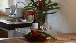 A kitchen counter with a bottle of wine, two glasses, and a bowl of fruit. - Rancho Las Tilapias (Parrita)