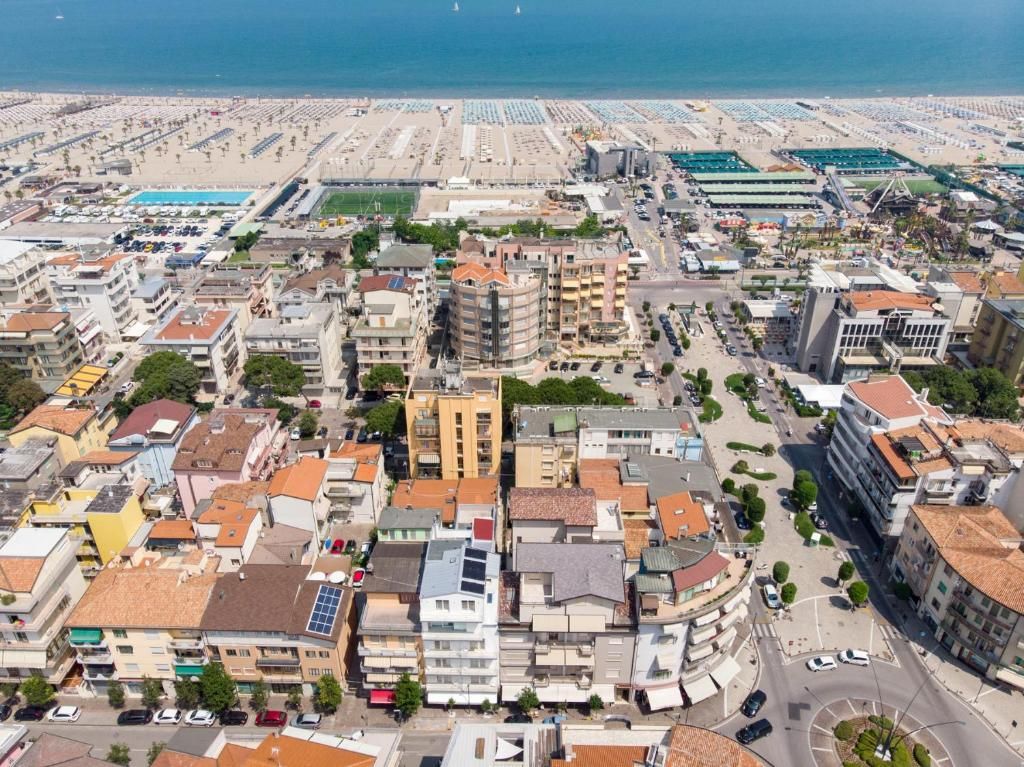 Une vue aérienne d’une ville côtière avec une plage, des bâtiments et des routes.
