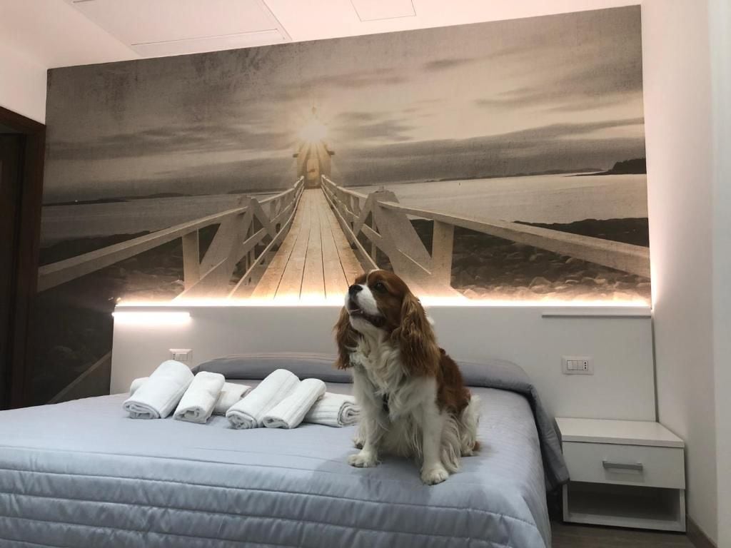 A bed with a headboard that has a painting of a bridge and a sunset. There are towels on the bed.