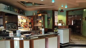 A bar area with a counter, shelves with bottles, and a coffee machine.
