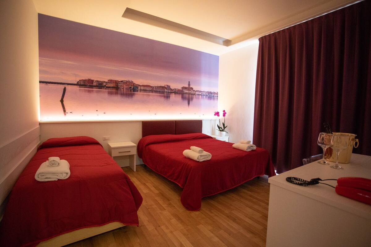 Une chambre d’hôtel avec deux lits, un bureau, une grande fenêtre donnant sur la ville et un mini-bar.