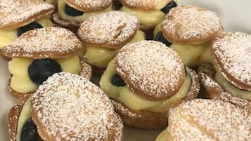 Een bord met profiteroles, bestrooid met poedersuiker en bosbessen.