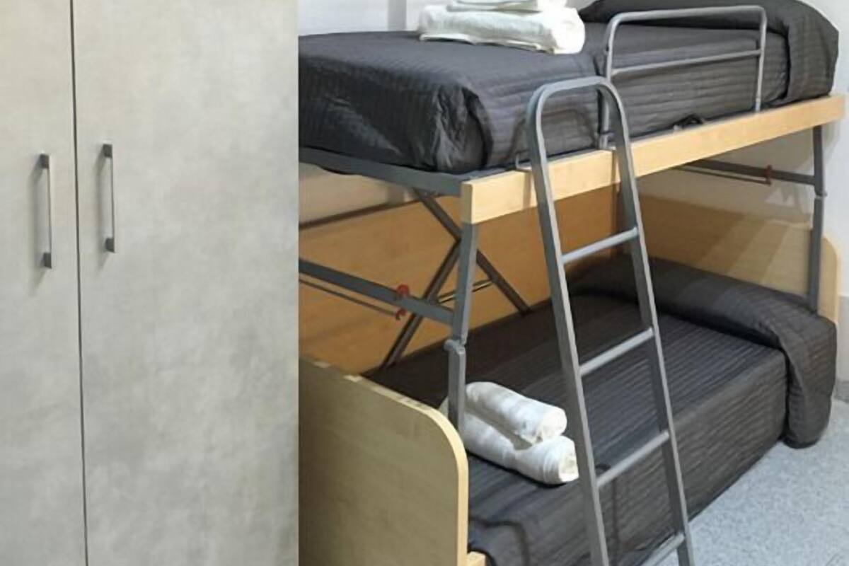 Une chambre avec un lit superposé, une armoire et une étagère au-dessus du lit.