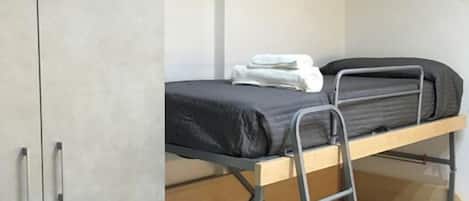 Une chambre avec un lit superposé, une armoire et une étagère au-dessus du lit.