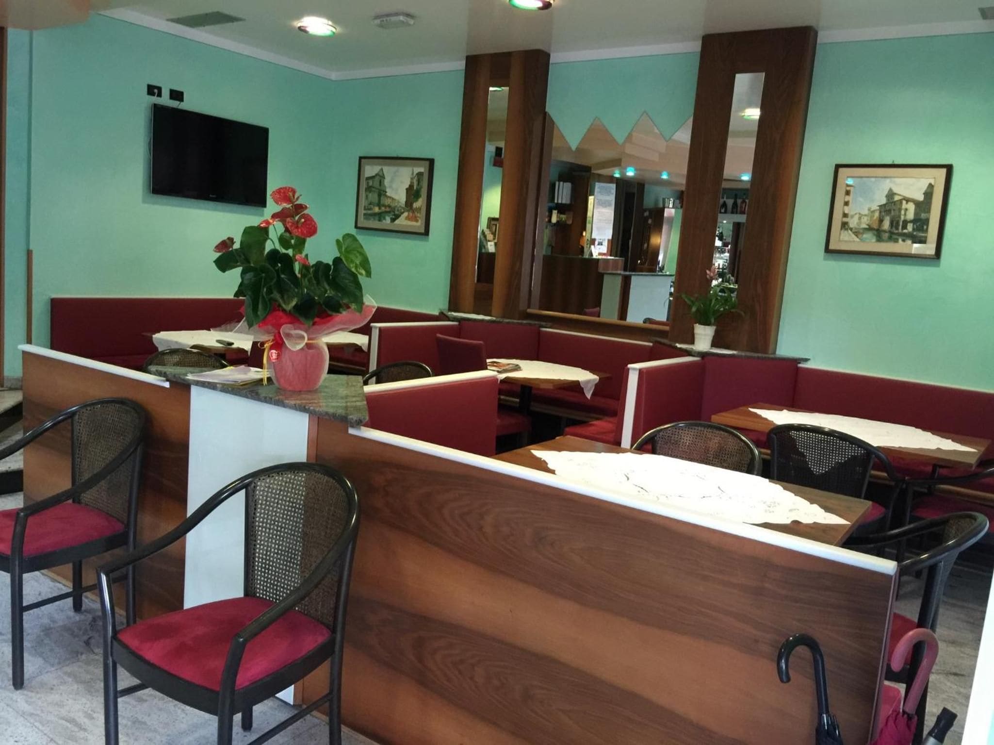 Un hall de hotel con mostrador de recepción, zona de estar y un televisor montado en la pared.