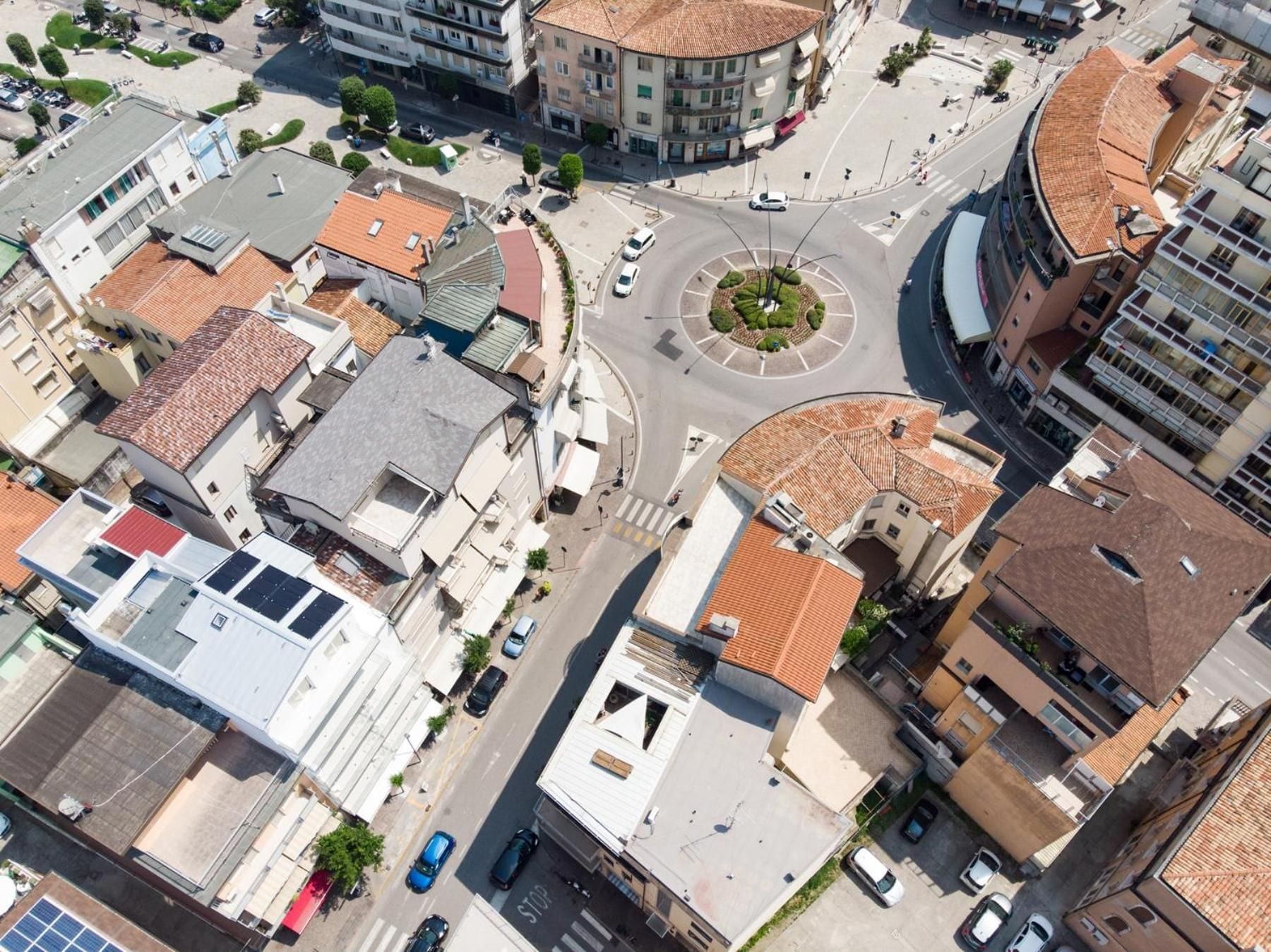 An aerial view of a city intersection with buildings, roads, and a roundabout.