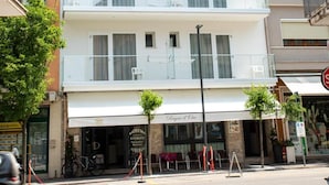 A multi-story building with balconies, a restaurant at the ground level, and a parking sign.
