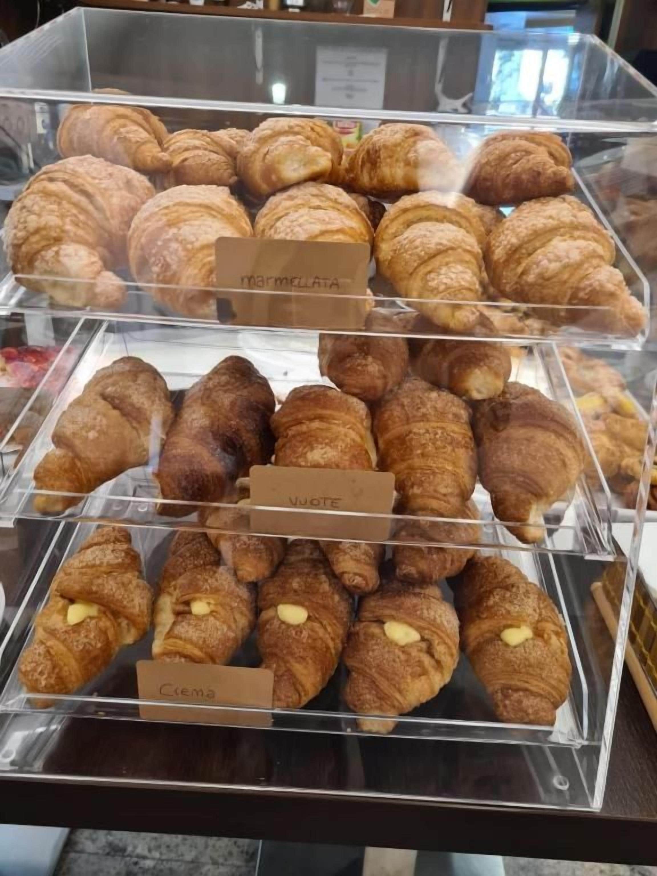 A bakery display case with various types of pastries, including croissants and other baked goods.
