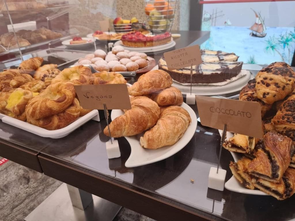 Mostrador de panadería con productos etiquetados, incluyendo opciones veganas y de chocolate.